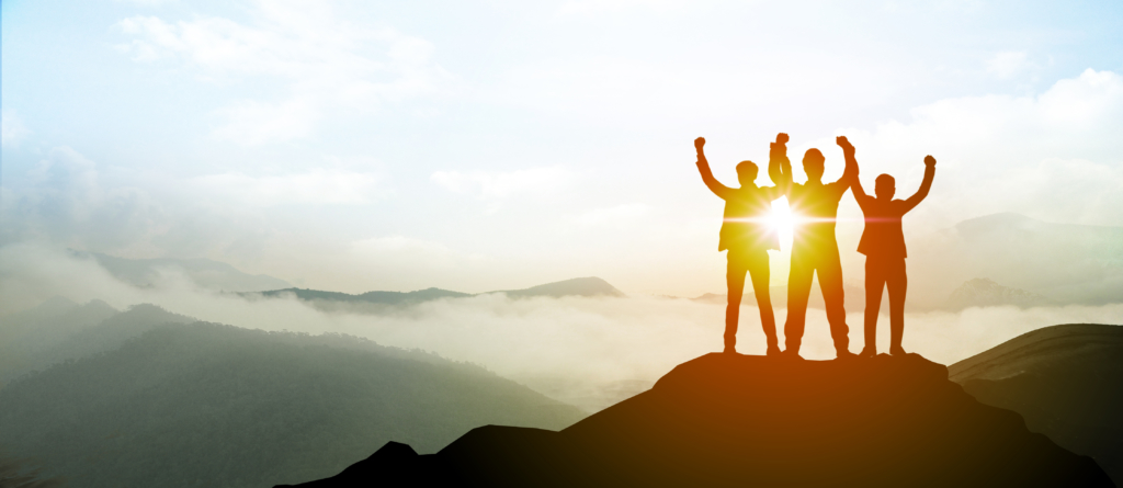 Silhouette of Business team show arm up on top of the mountain.